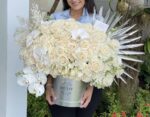 Round box of white roses with a palm leaf accent