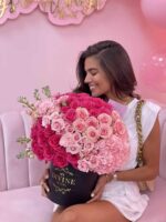 Woman holding a Carla round box of pink flowers