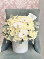 Round white box filled with cream roses