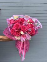Hand bouquet of bright pink roses wrapped in paper
