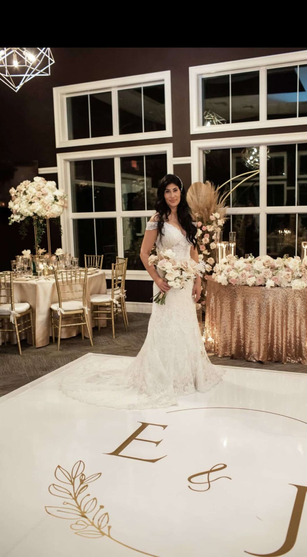 Bride on the dance floor of a Miami wedding reception with tall white rose centerpieces and pampas
