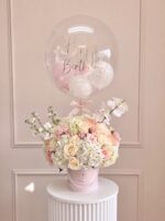 Susan: rosas crema y durazno con hortensias y orquídeas en caja rosada con perlas y globo burbuja Happy Birthday