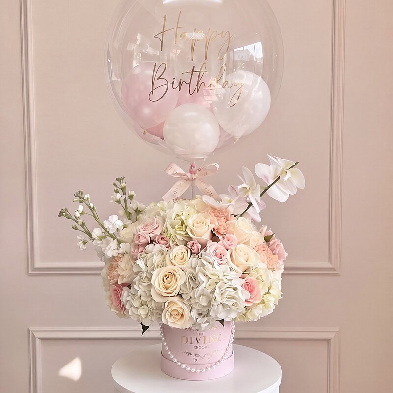Susan: rosas crema y durazno con hortensias y orquídeas en caja rosada con perlas y globo burbuja Happy Birthday