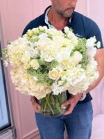 White and pink arrangement held by the florist