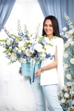 Woman holding the Blue Imperiale hat box with blue and white flowers