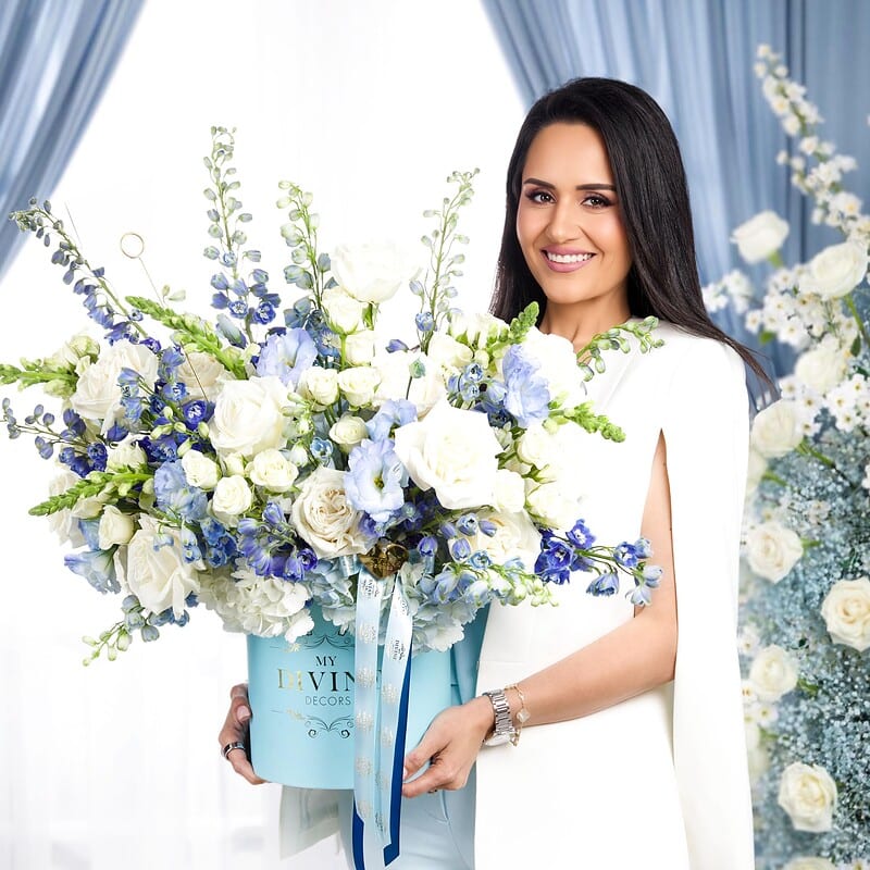 Mujer sosteniendo la caja sombrero Blue Imperiale con flores azules y blancas