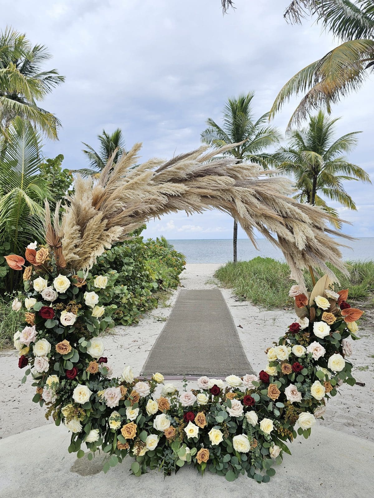 Arco de boda circular con flores y pampas frente al mar en Miami