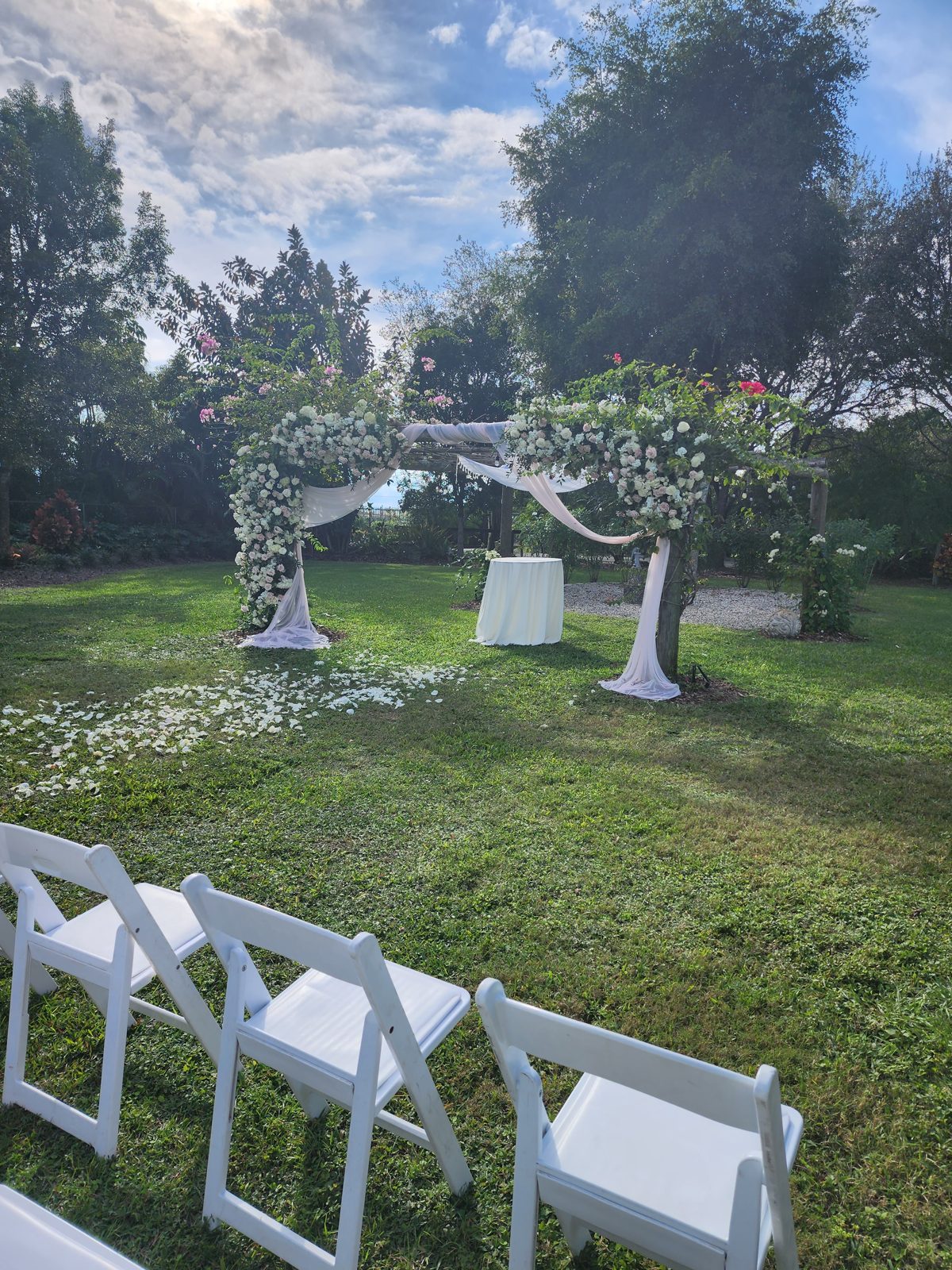 Ceremonia de boda en jardín con sillas blancas y arco floral en Miami