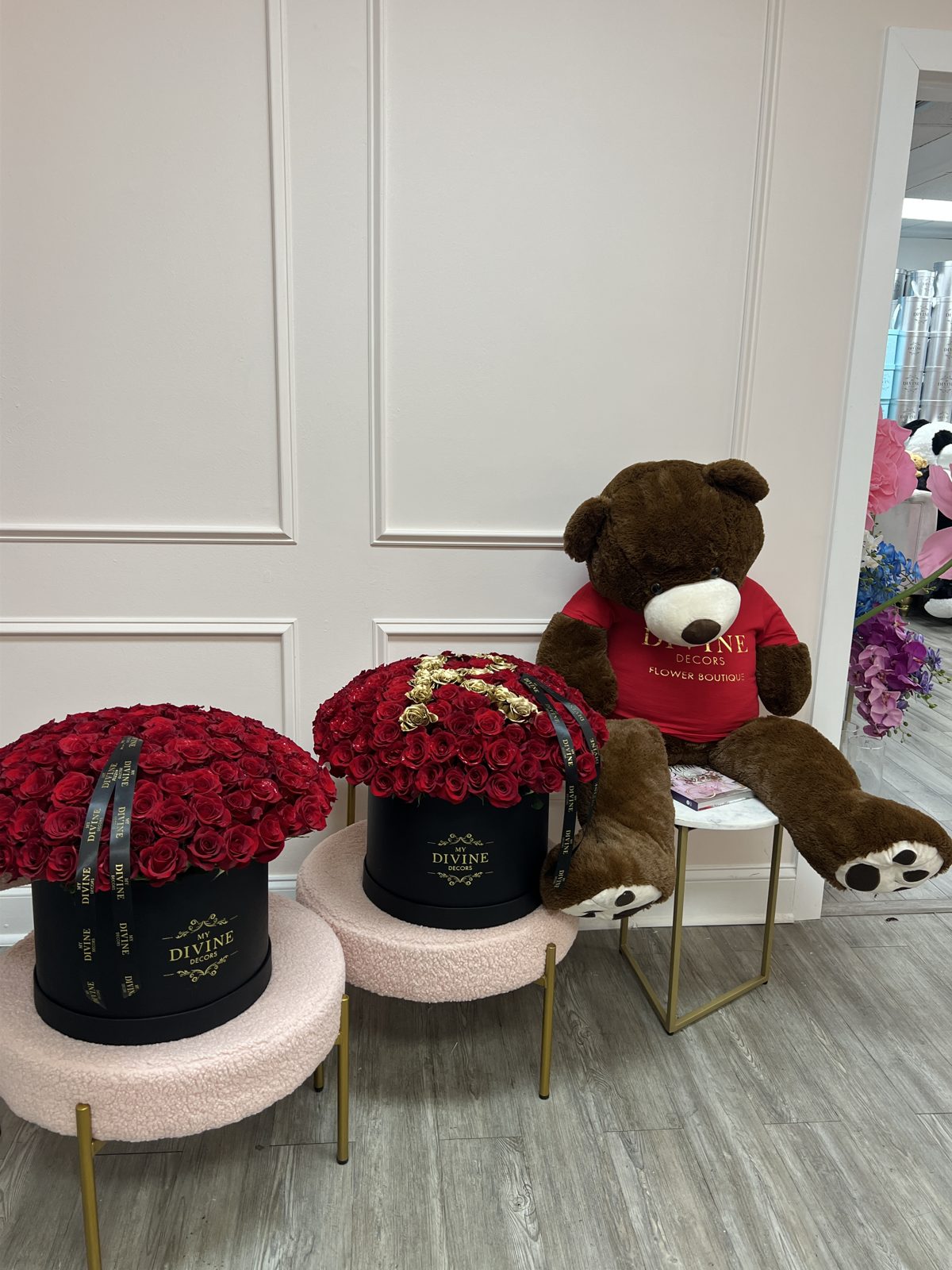 Giant brown teddy bear seated next to two boxes of red roses at the Miami studio