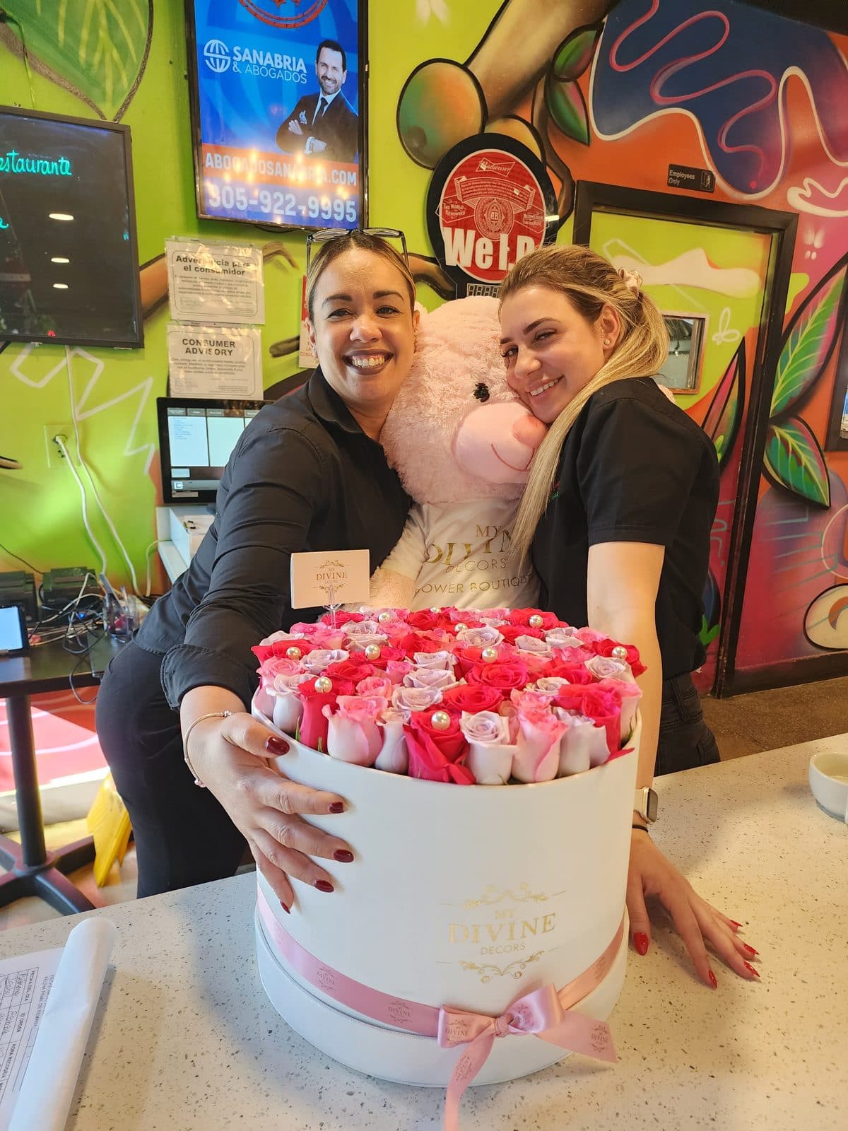 Two women receiving a giant pink teddy bear with a large rose box delivered in Miami