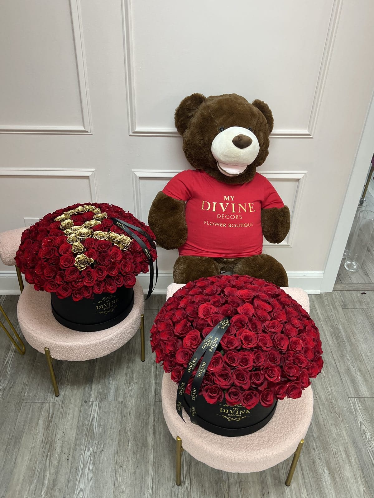 Giant brown teddy bear in a My Divine Decors shirt between two rose box arrangements in Miami