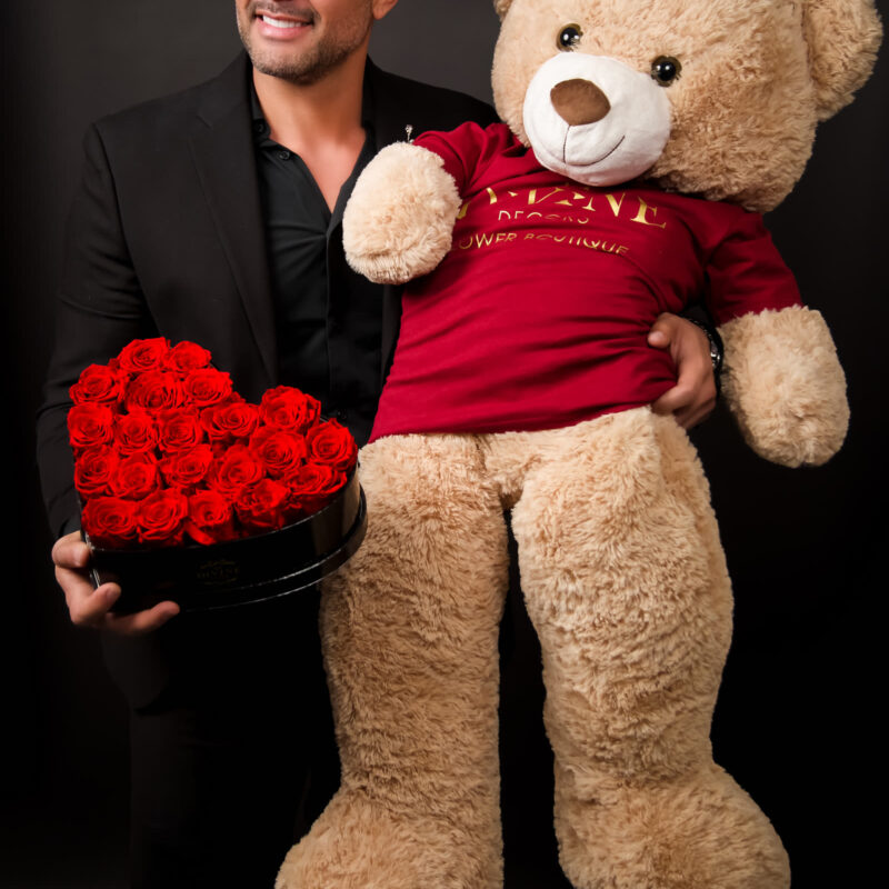 Nelson Ramirez holding a custom teddy bear dressed in a My Divine Decors branded shirt with a heart of red roses