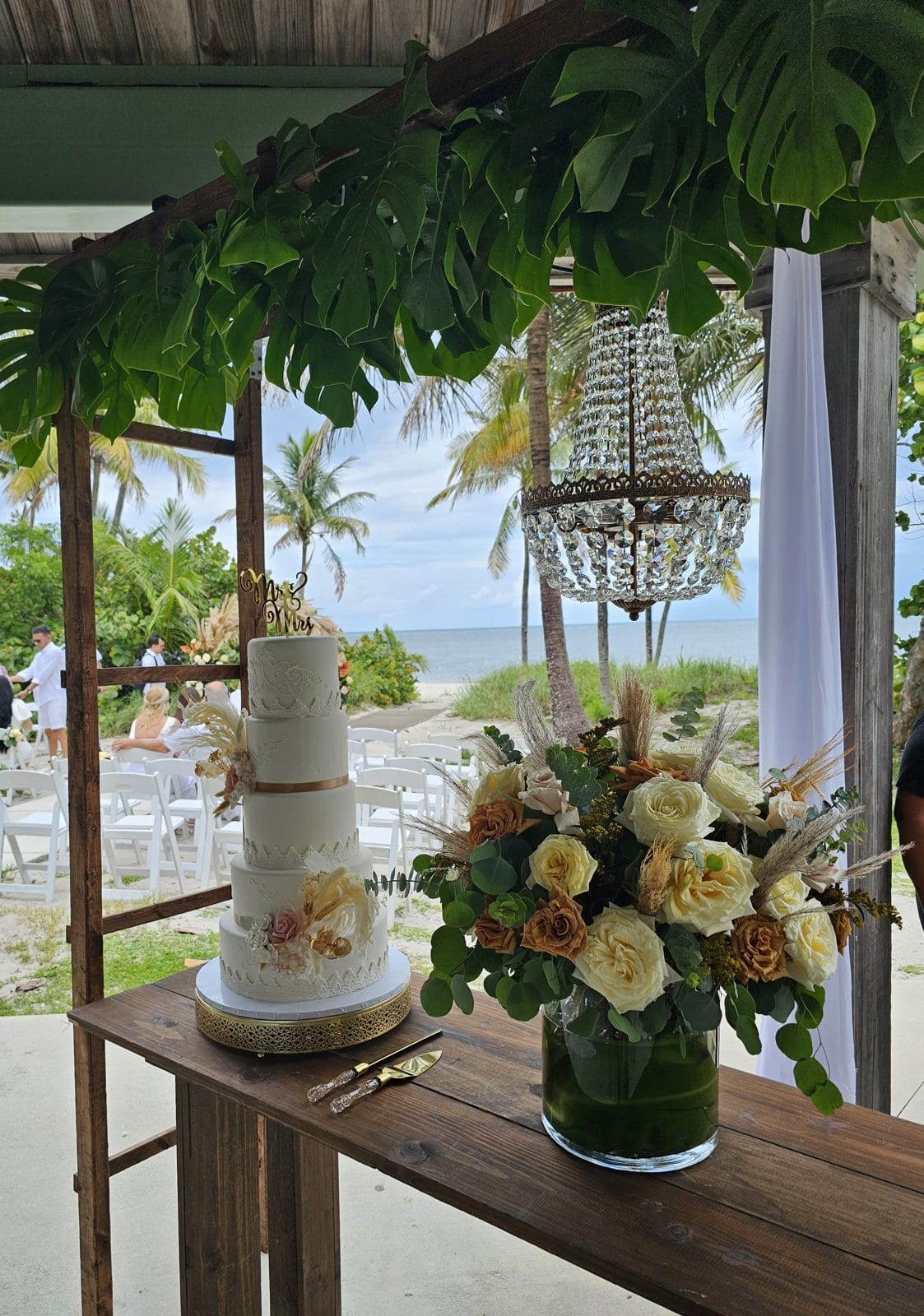 Mesa de pastel decorada con flores frescas en una boda frente al mar en Miami
