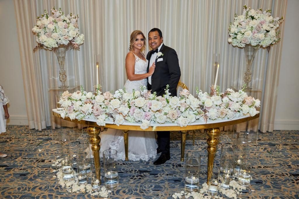 Novios en la mesa principal decorada con arreglos florales en Miami
