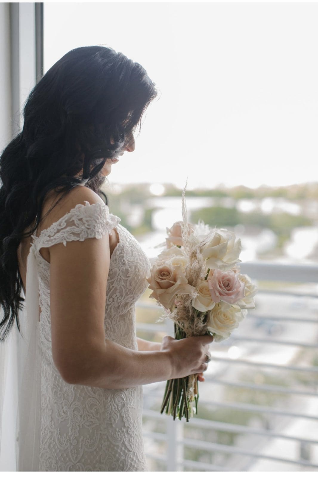 Novia con su ramo de rosas blush junto a la ventana antes de la ceremonia en Miami