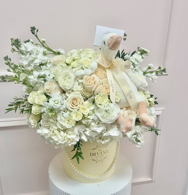 Cream and ivory flower hat box with a plush goose and pearl detail