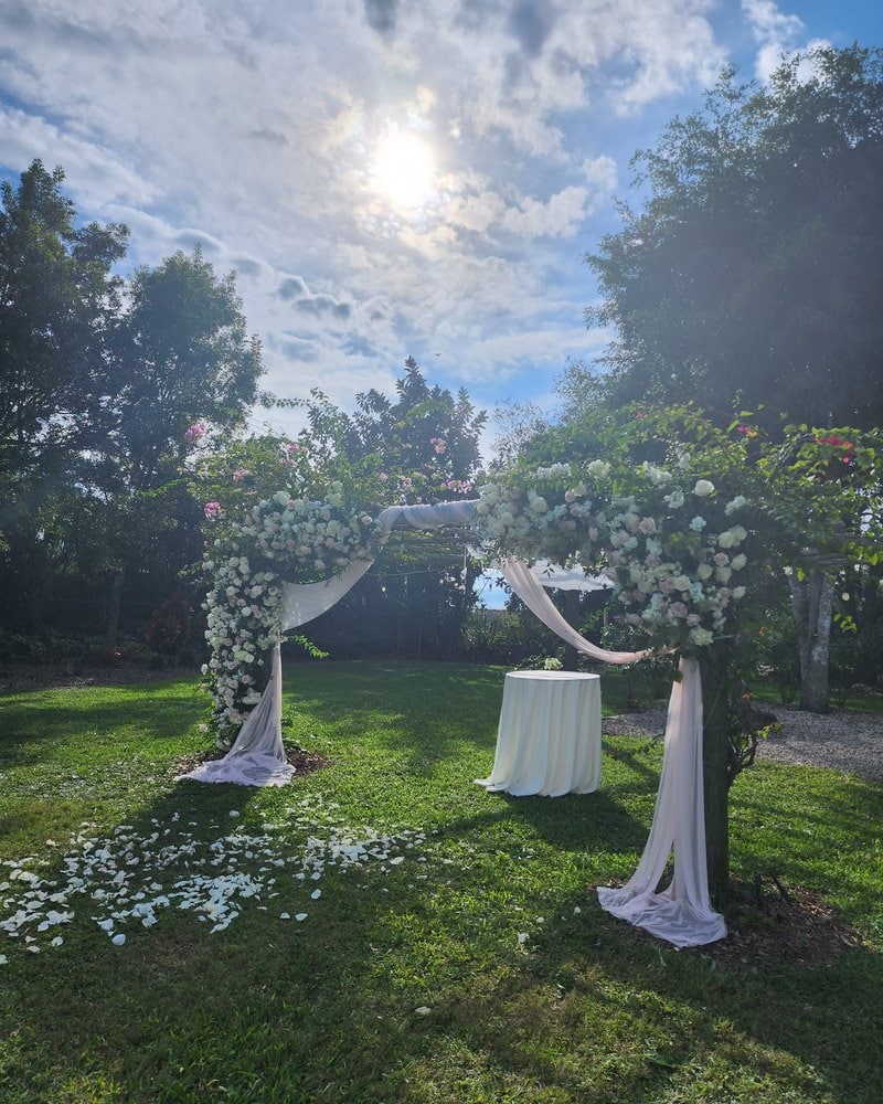 White roses, hydrangeas and babyโs breath on a garden ceremony structure in Miami