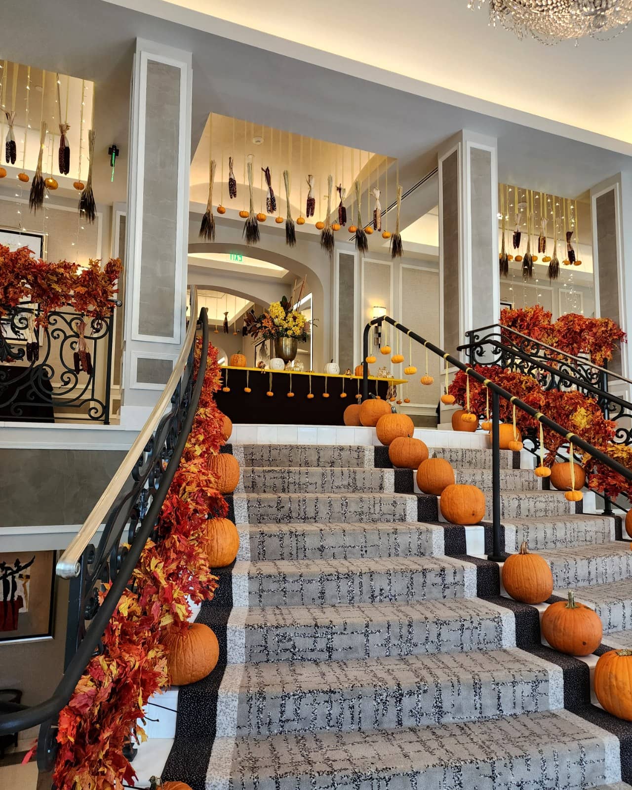 Fall garland and pumpkins on a Miami lobby staircase, seasonal installation by My Divine Decors
