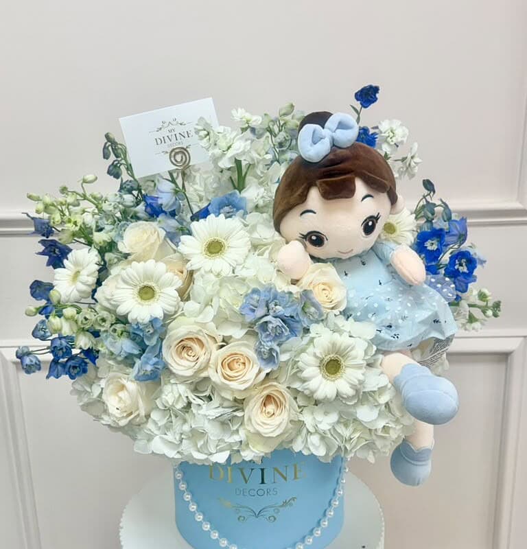 Blue hat box of white and blue fresh flowers with a plush doll
