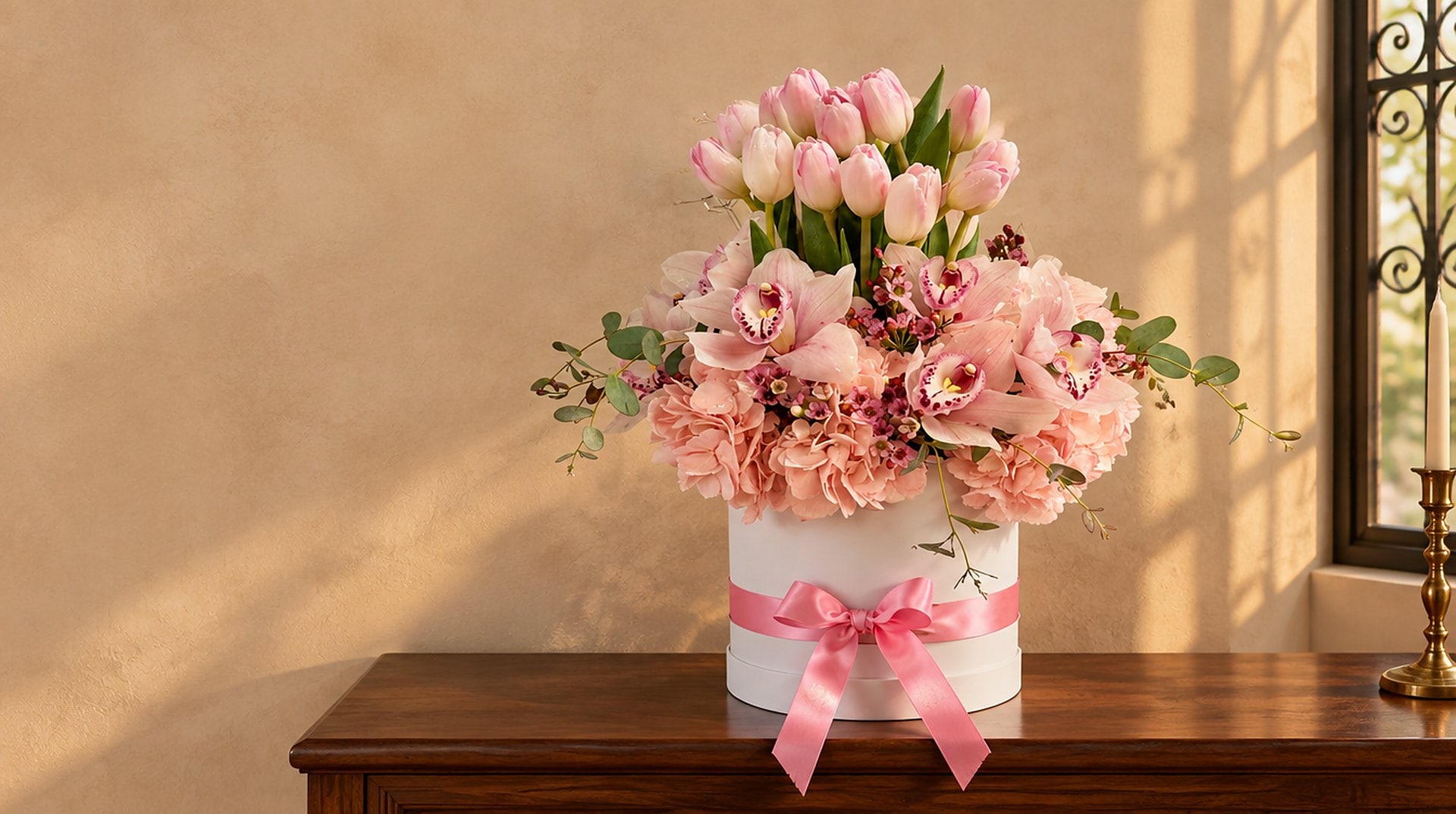 Caja sombrero de tulipanes rosados y orquídeas cymbidium sobre una consola de nogal en Coral Gables