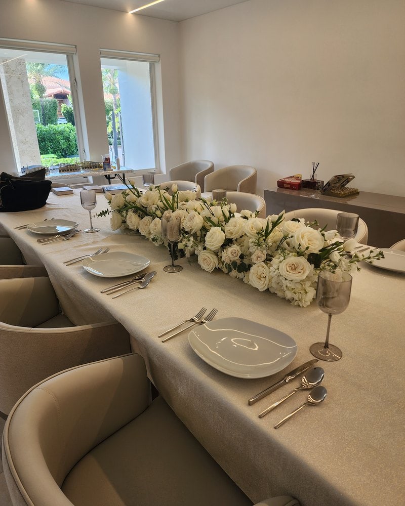 Shabbat dinner table with a runner of white roses and hydrangeas