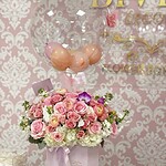 Anna con globo aerostático de My Divine Decors: globo burbuja transparente sobre una caja lila de rosas rosadas, ranúnculos, hortensias blancas y orquídeas