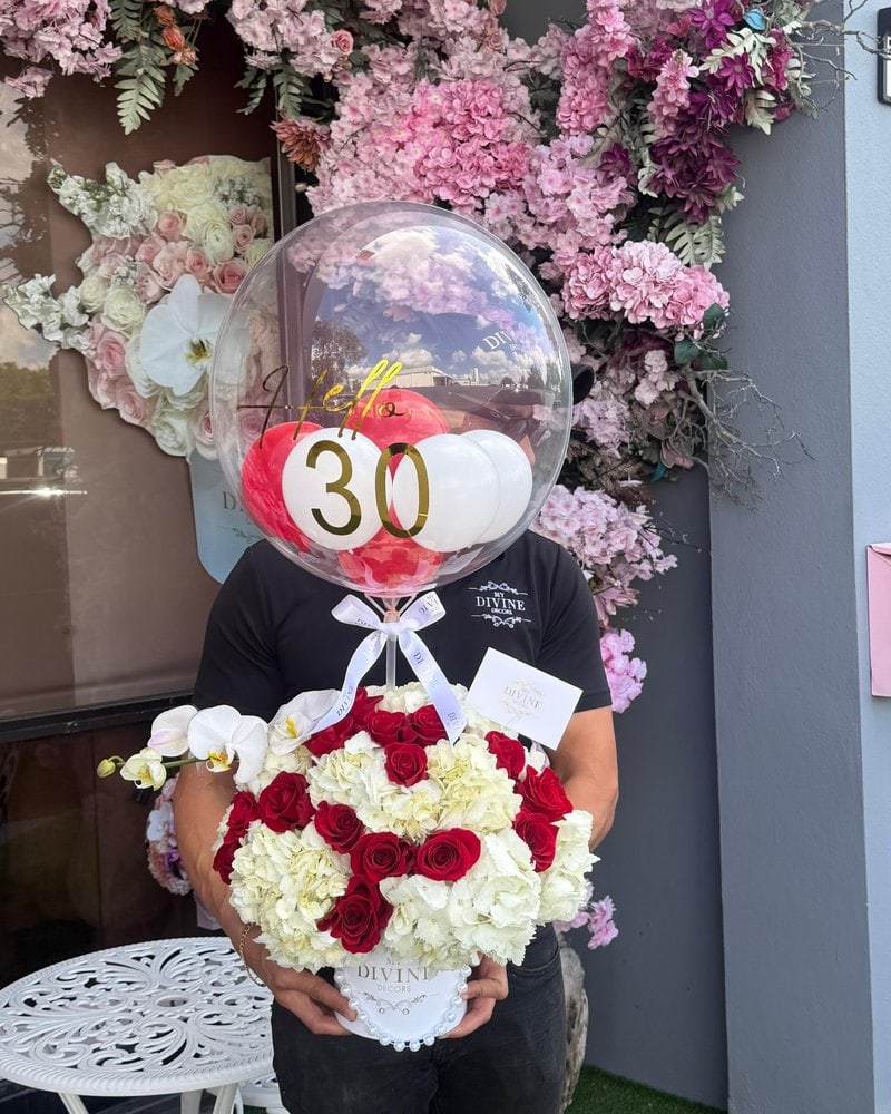 Customer picking up a number 30 bubble balloon and roses at the door of our Doral flower shop