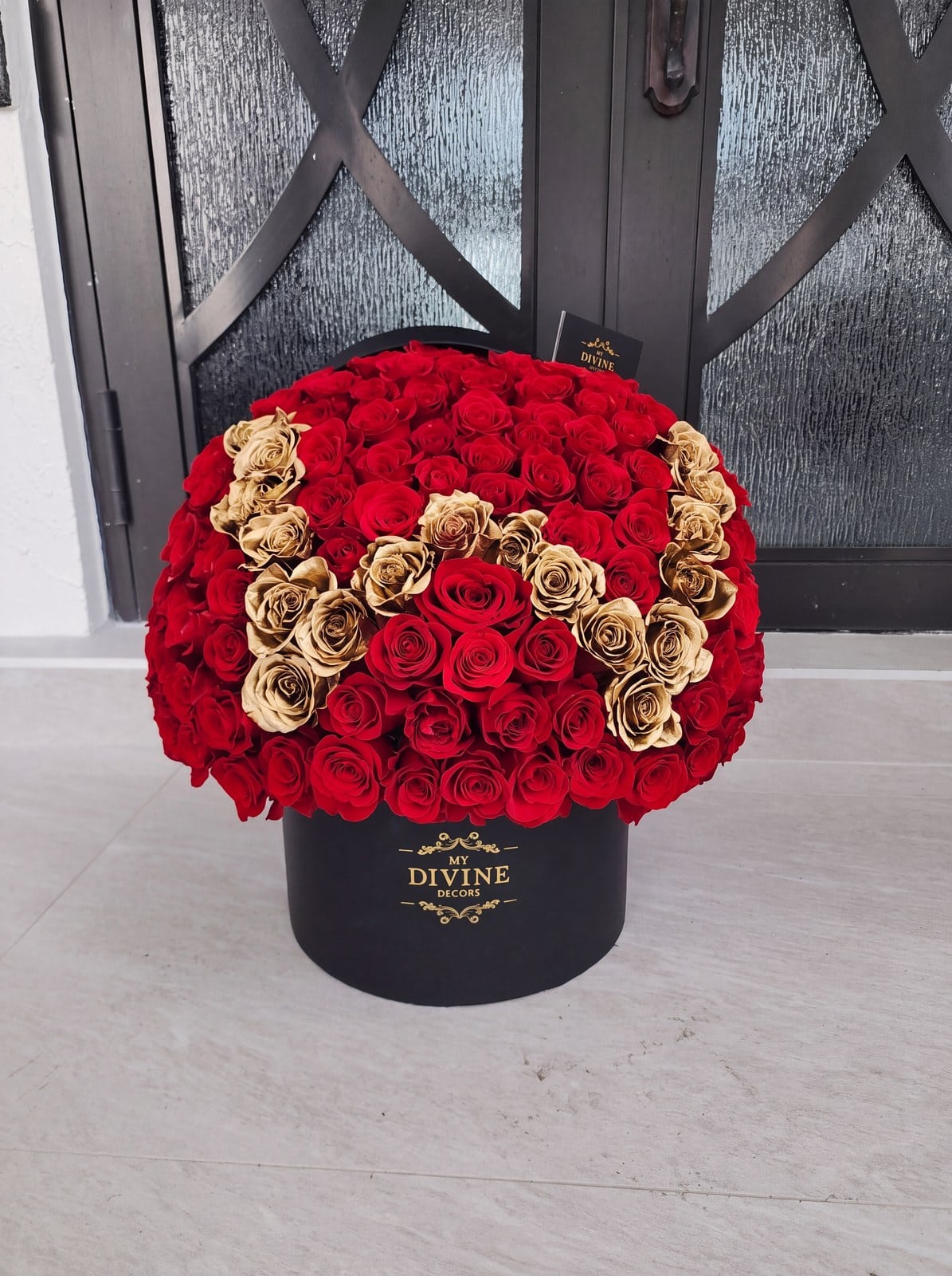 Grand box of red roses with an initial in gold roses by My Divine Decors waiting at a front door in Miami