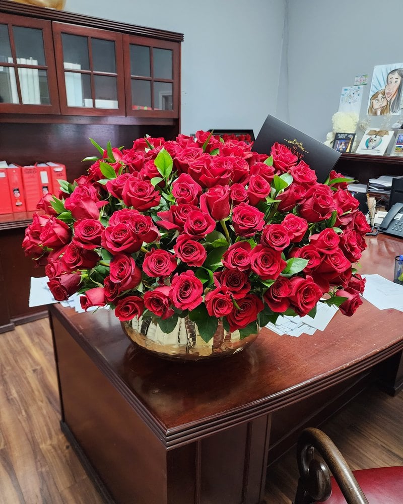 Red rose arrangement in a gold bowl on an executive desk