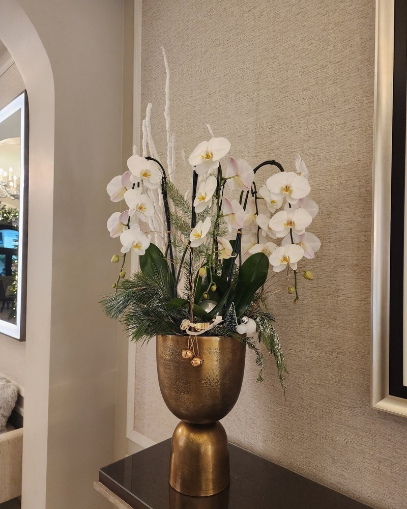 White phalaenopsis orchids in a gold footed vase on a lobby console in Miami