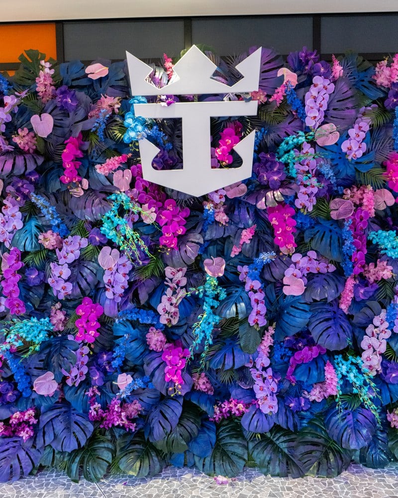 Purple and blue flower wall with the Royal Caribbean crown and anchor