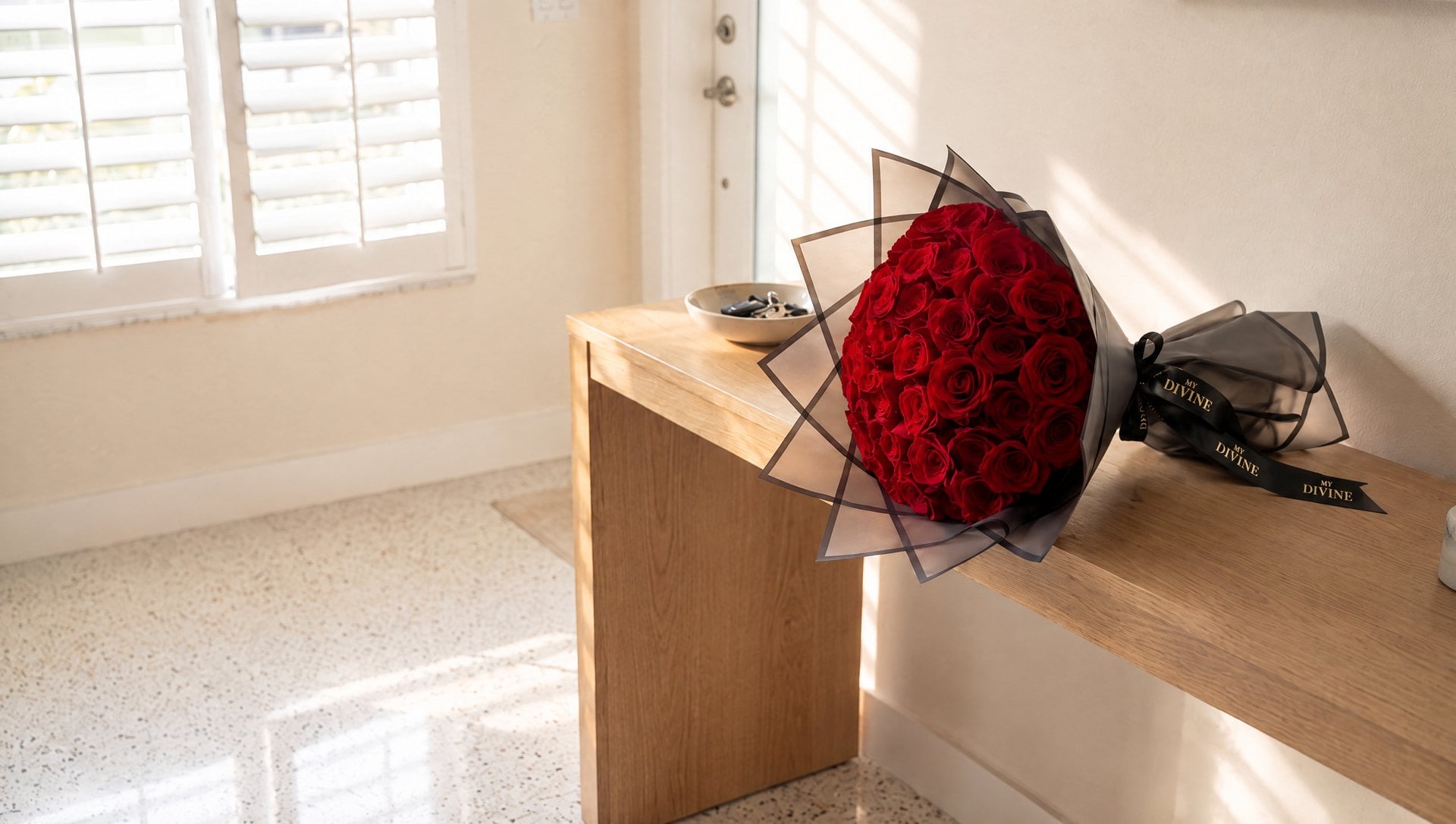 Ramo Buchón de rosas rojas con cinta MY DIVINE sobre una consola junto a la puerta de una casa en Hialeah