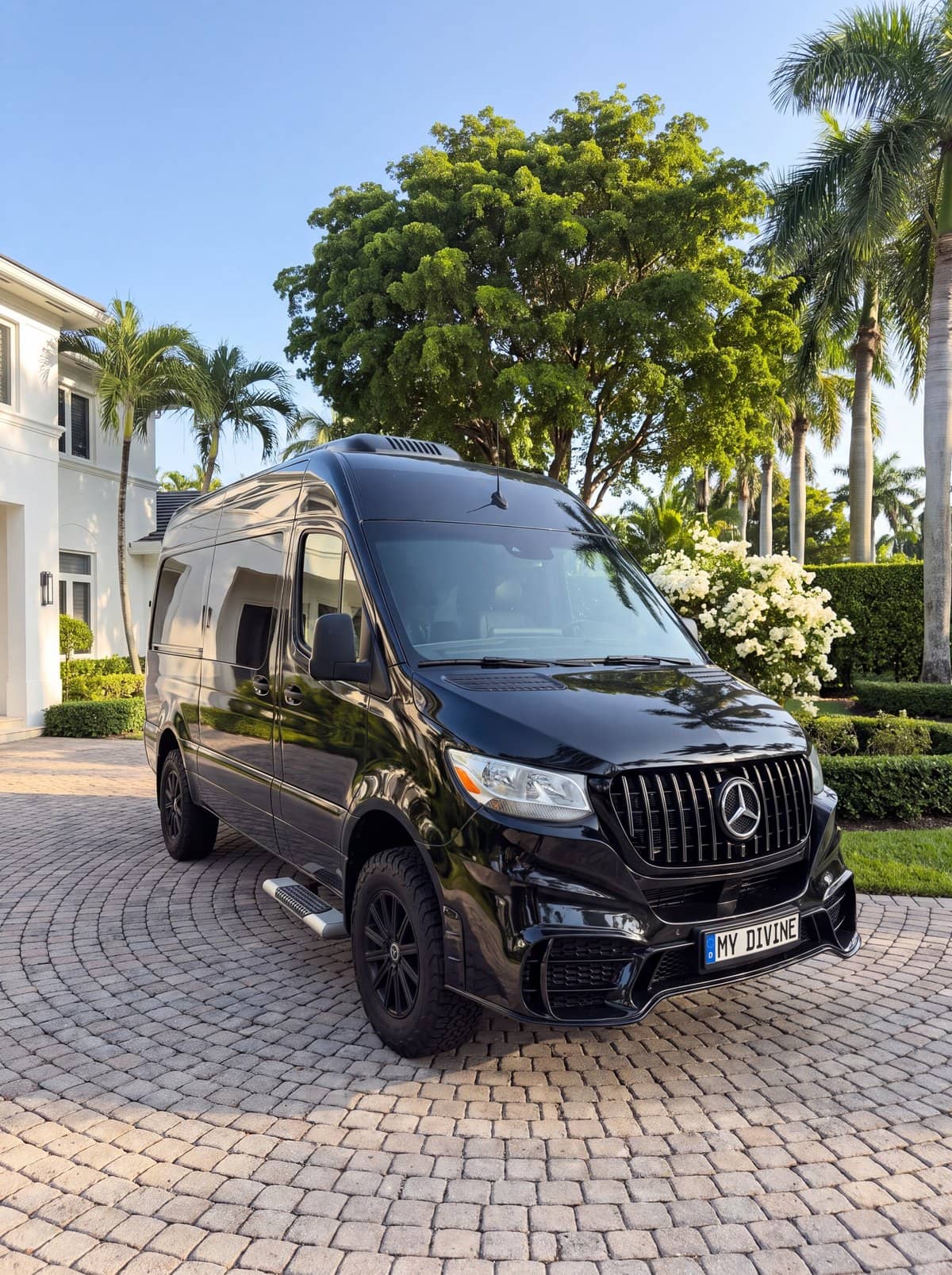 Camioneta Mercedes negra de My Divine Decors con placa MY DIVINE frente a una casa