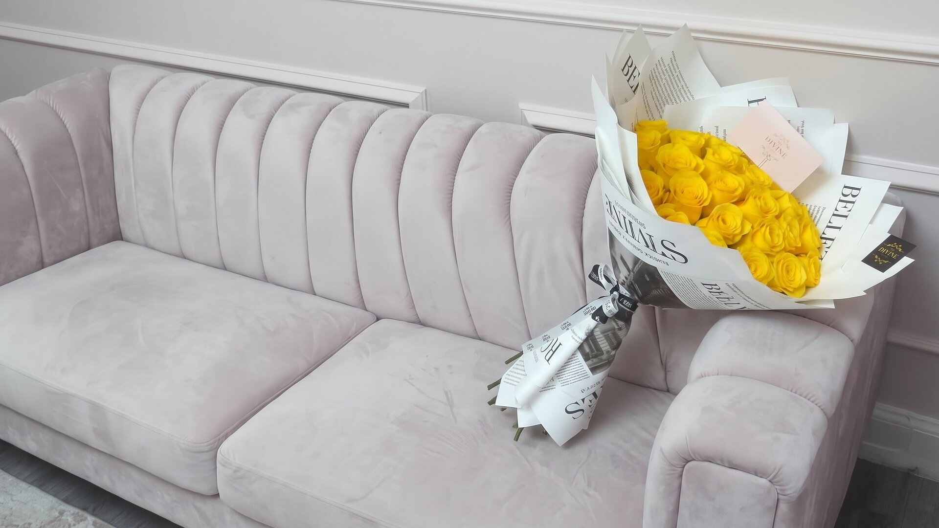 Ramo buchón de rosas amarillas de My Divine Decors envuelto en papel de periódico sobre un sofá