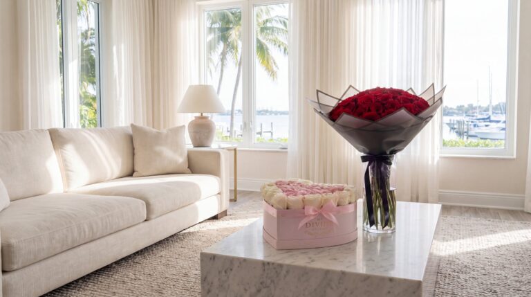 Una caja de corazón rosada de My Divine Decors con rosas blancas y rosadas y un ramo buchón de rosas rojas en un florero de cristal sobre una mesa de mármol en una sala de Coconut Grove un domingo por la mañana
