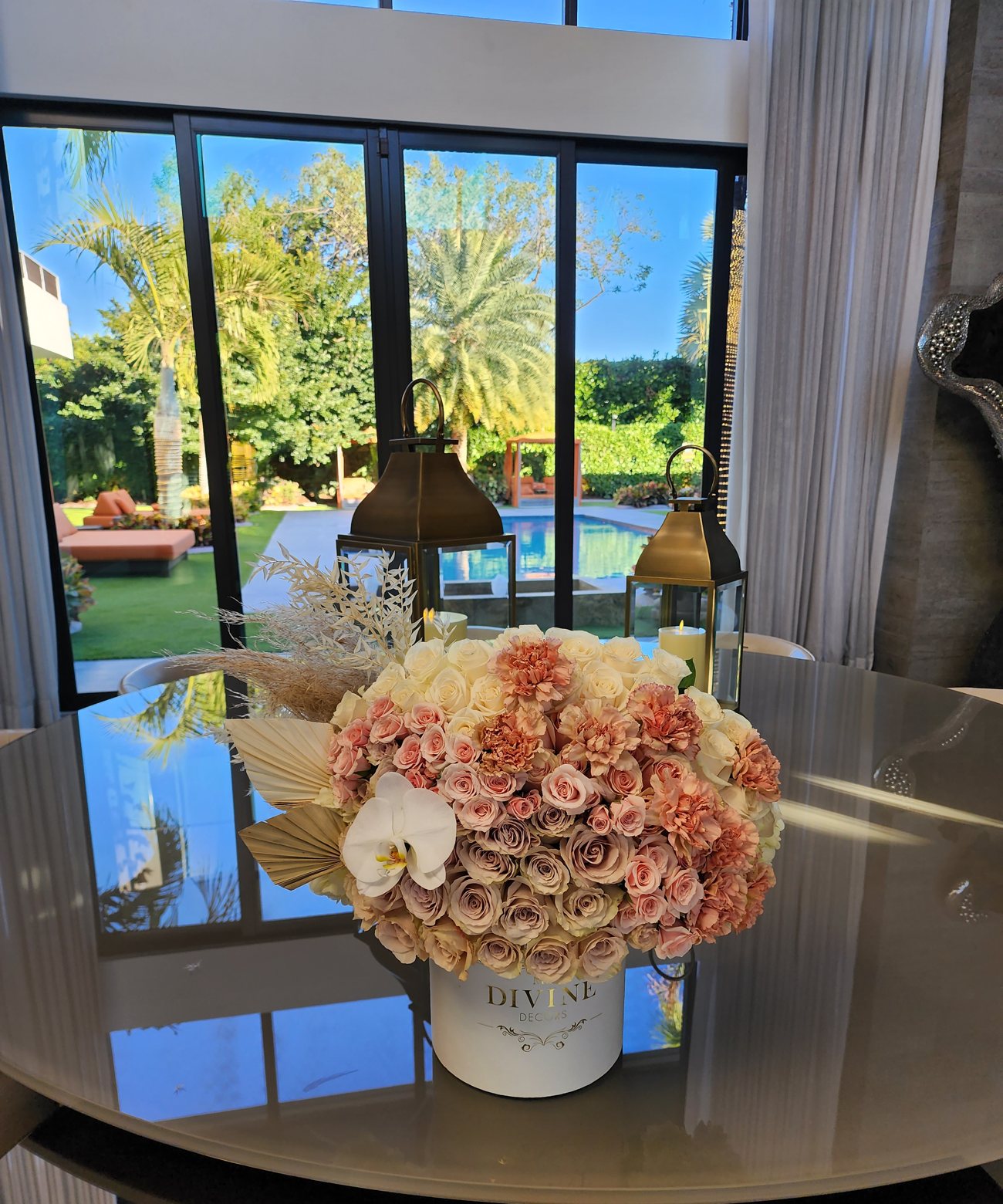 Peach and blush roses with pampas and a white orchid in a white My Divine Decors box on a dining table facing a pool in Miami
