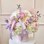 Hanna medium signature box: pink ranunculus, blush roses, white orchids, hydrangea and lavender stock with a lilac ribbon