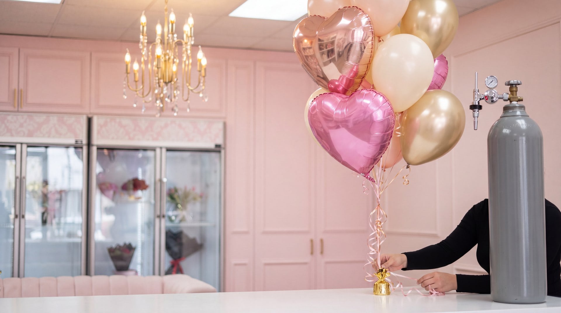 Helium tank and a bouquet of pink, ivory and gold balloons tied to a weight on the counter of our Doral flower studio