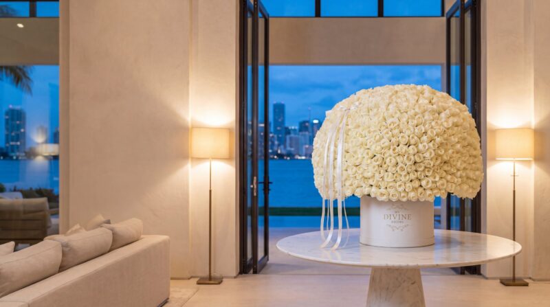 My Divine Decors Grand 1000 white roses signature arrangement on a marble table in a waterfront villa on Star Island at dusk, with the Miami skyline behind
