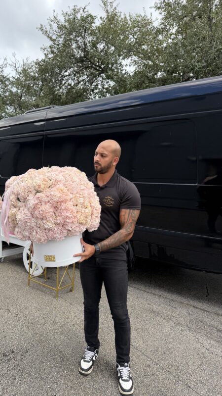 A staff member carries a hydrangea box beside the MY DIVINE van