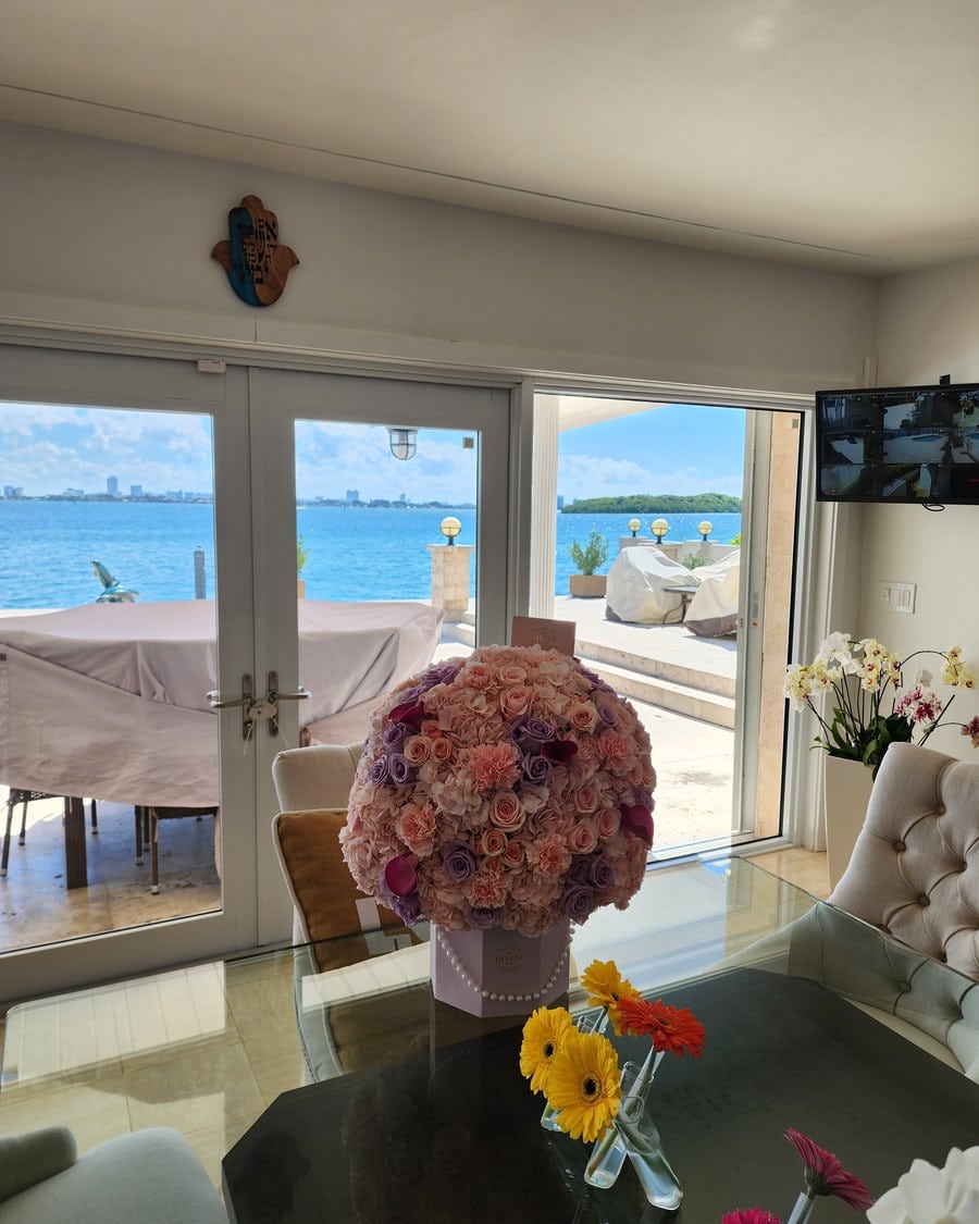A dome of mauve roses on a dining table facing the water in a Miami home