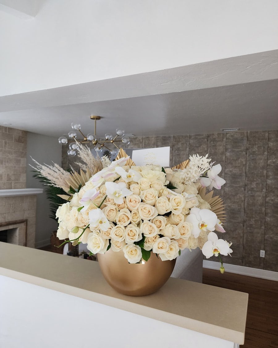 White roses and orchids in a gold bowl with pampas, delivered to a Miami home