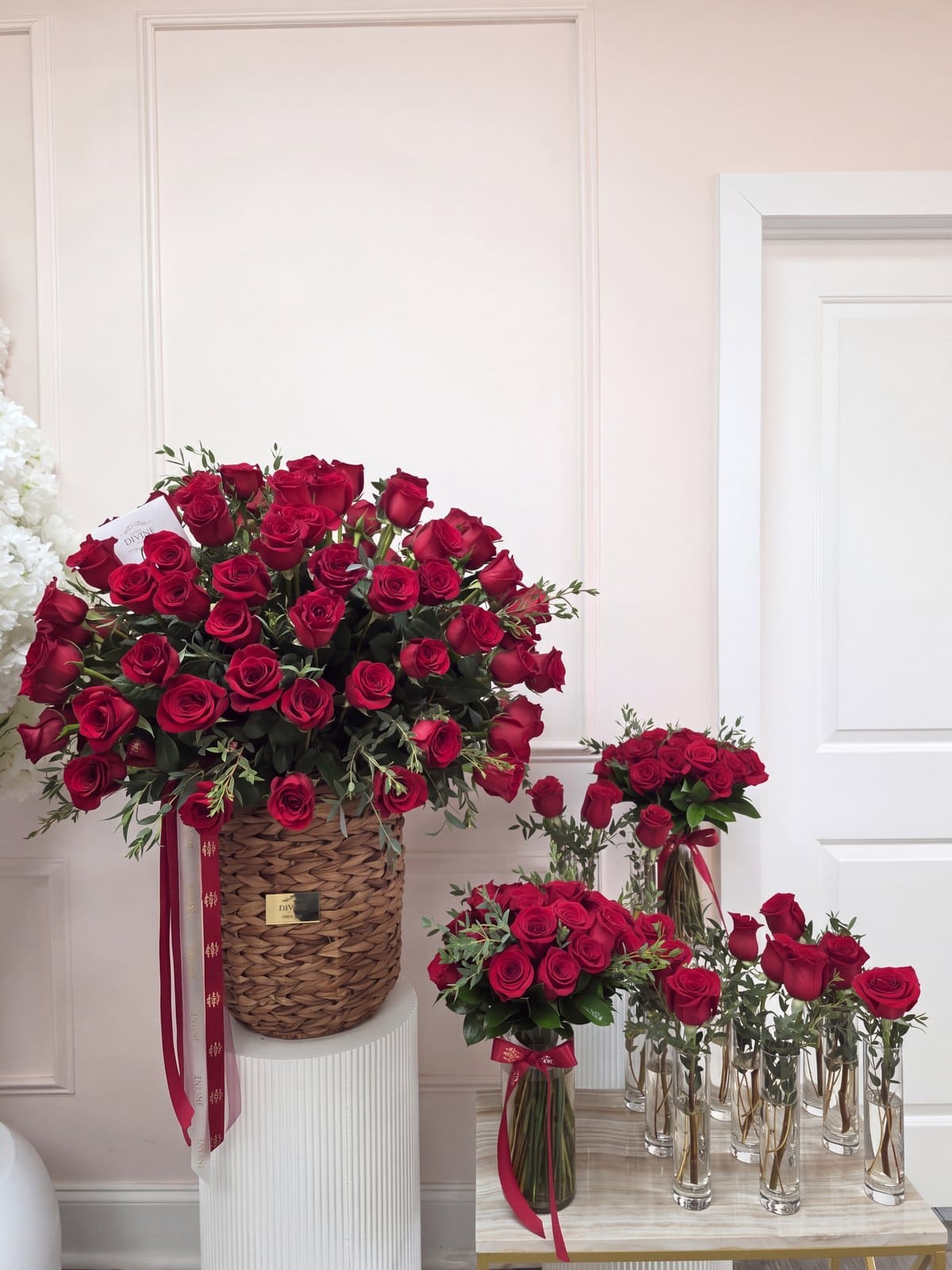 El juego completo para un jet privado en el taller de My Divine Decors en Doral: canasta tejida de rosas rojas sobre un pedestal, un florero de rosas rojas con lazo rojo y una fila de rosas rojas sueltas en floreros altos