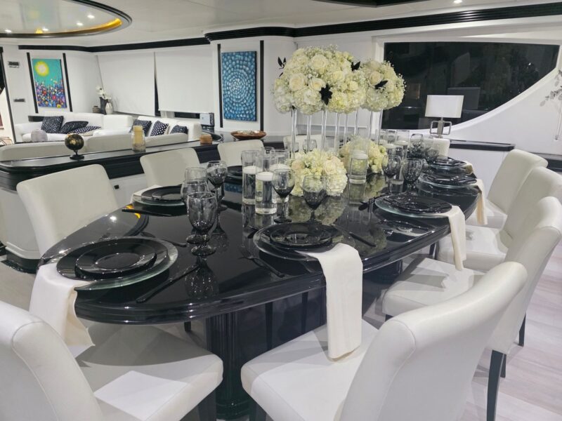 Private yacht dinner in Miami with tall white rose and hydrangea centerpieces on glass columns and floating candles