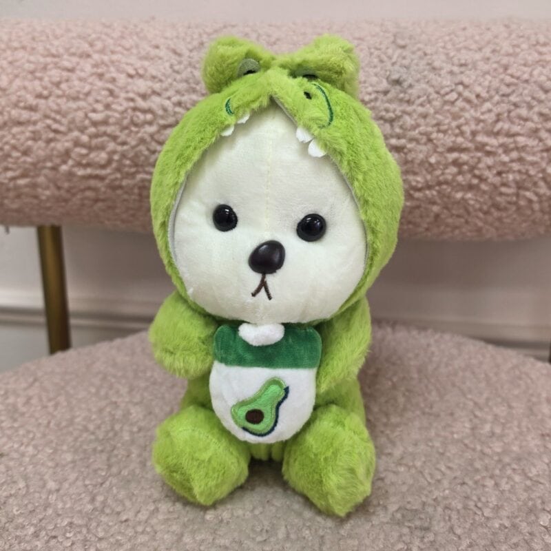 Osito de peluche blanco con disfraz de dinosaurio verde y babero con aguacate