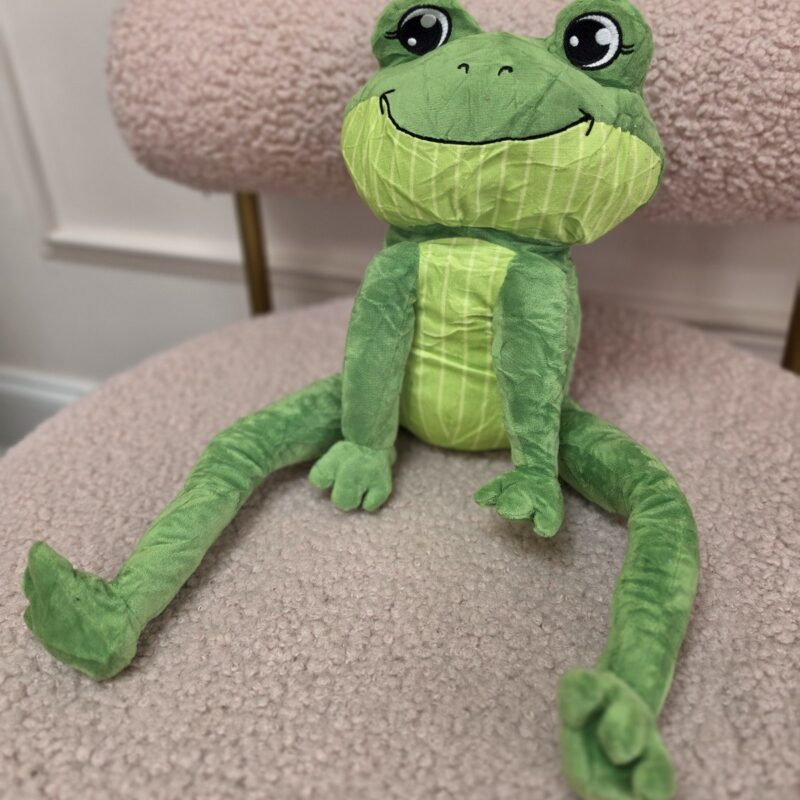 Rana de peluche verde con patas largas colgantes y sonrisa grande