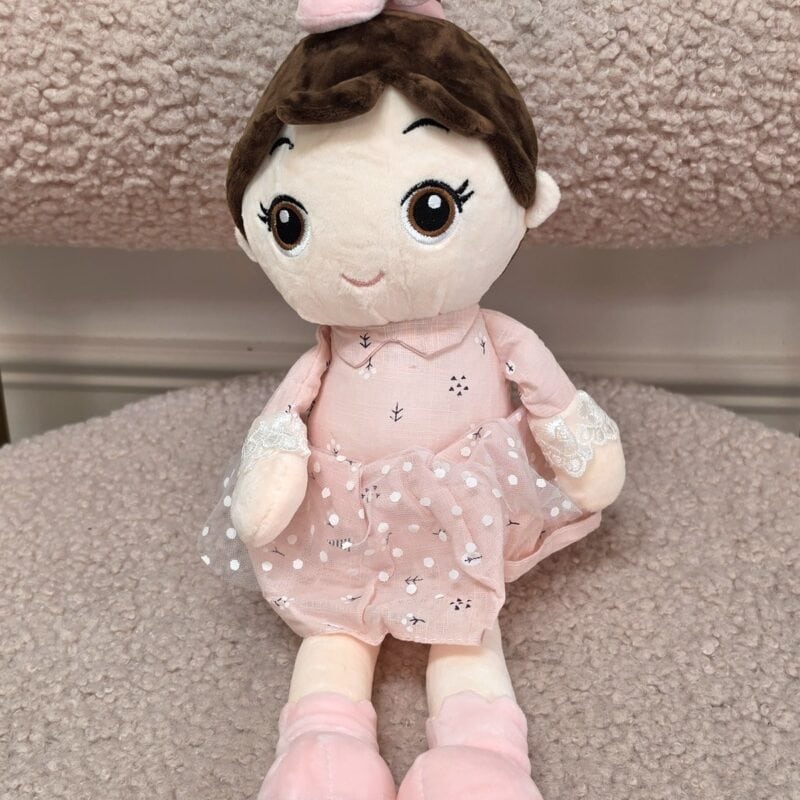 Muñeca de peluche de cabello café con vestido rosado, falda de tul y moño rosa