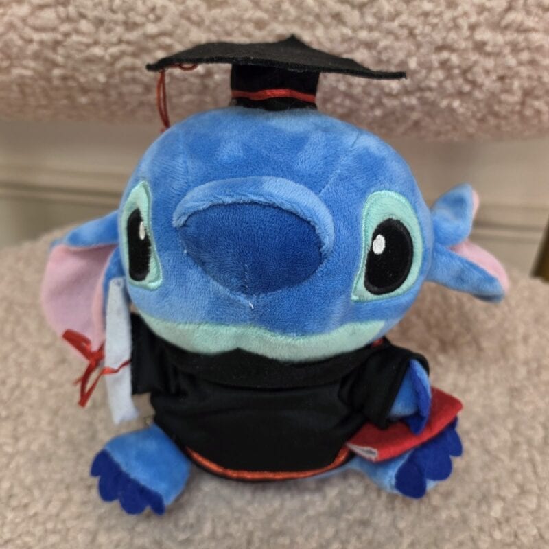 Peluche Stitch con birrete y toga negra de graduación y diploma