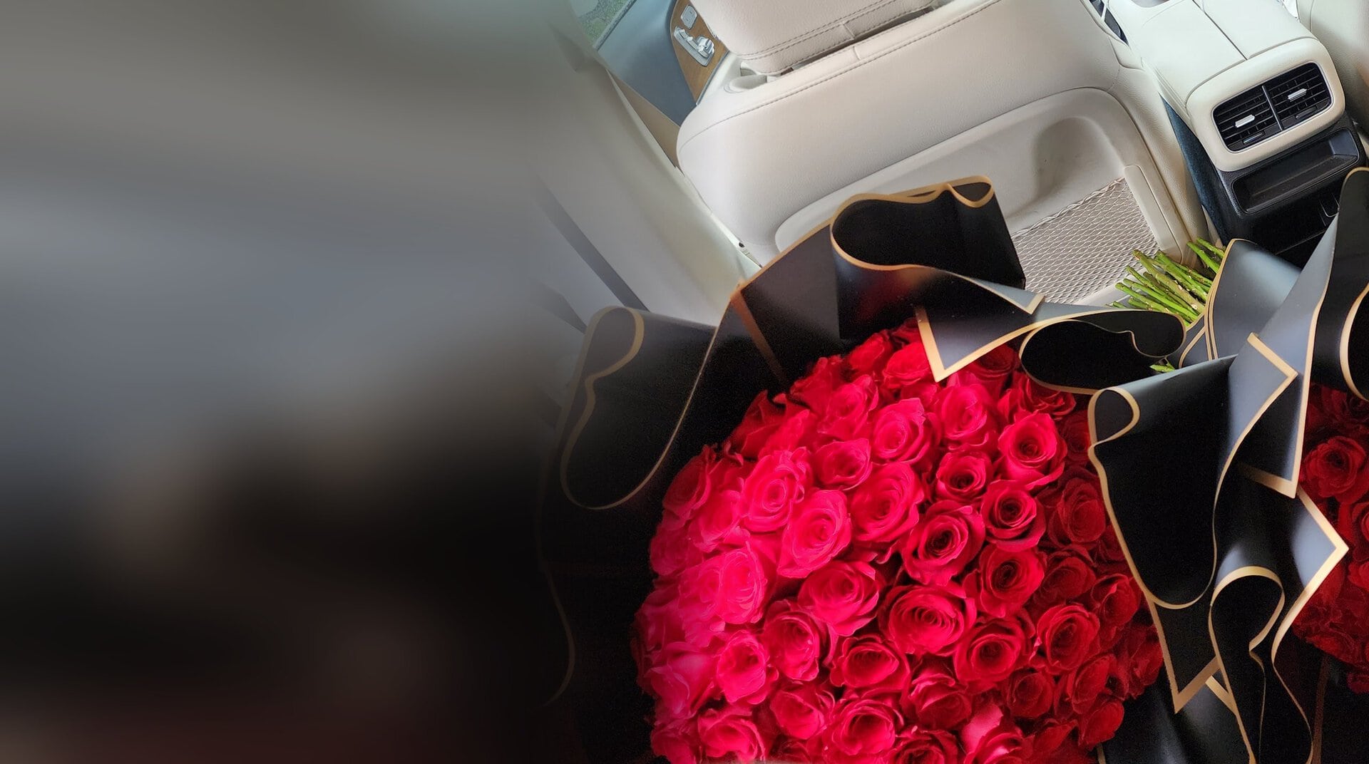 Dos ramos buchón de My Divine Decors con rosas rojas y papel negro con borde dorado en el asiento de un carro de lujo en Miami