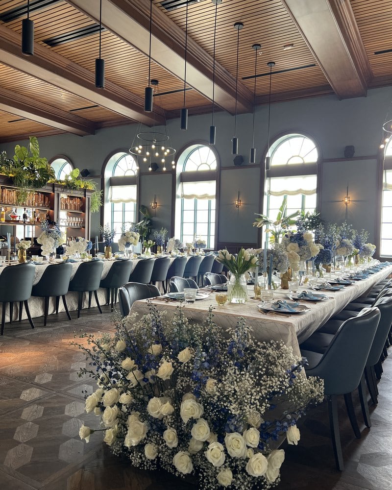Long restaurant table with a cascade of white roses and blue delphinium in Miami